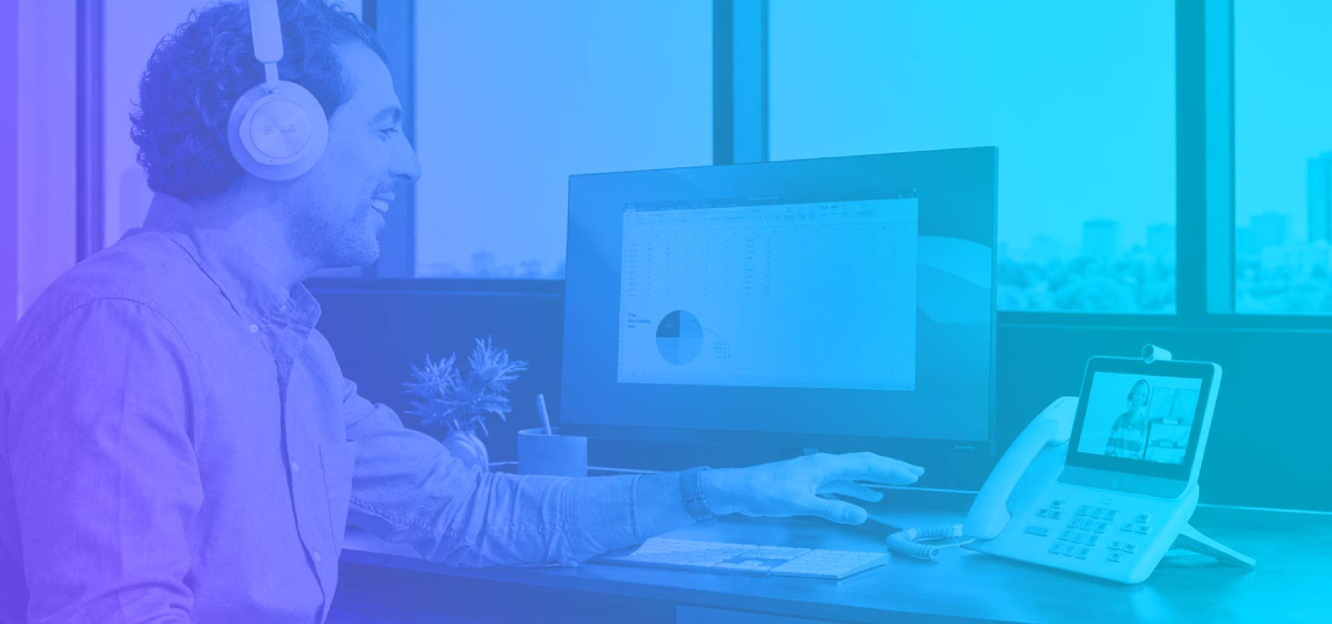 Man on Webex video call at desk with dual monitors, headset, and desk phone